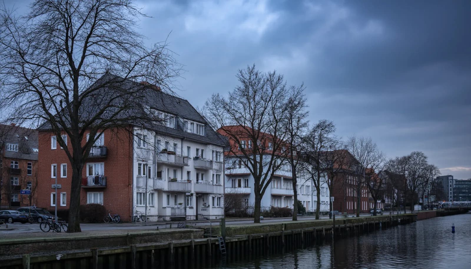 A quiet Winterhude canal street with brick apartment houses, bare trees and parked bicycles